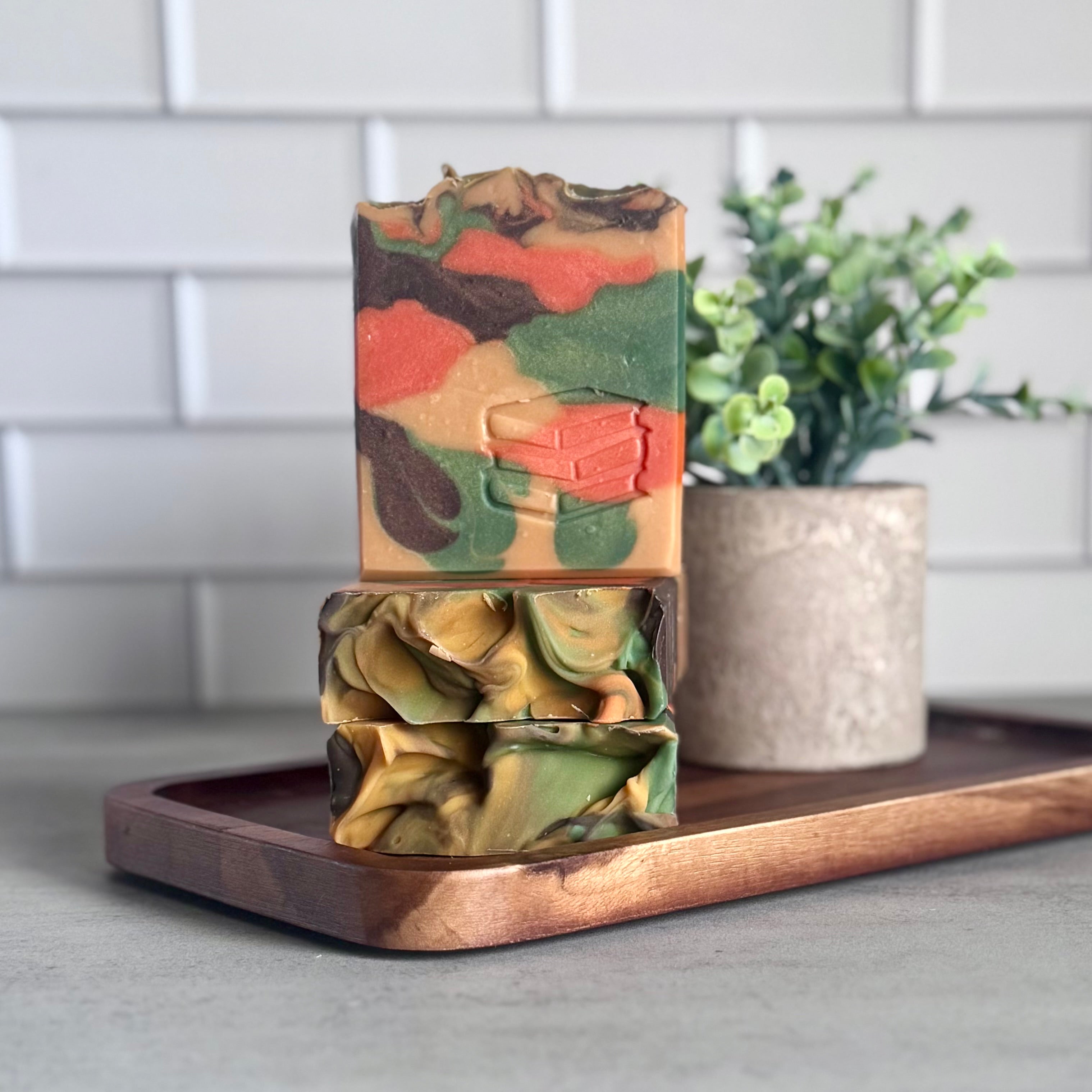 Stack of handcrafted artisan soaps from Harvest Soap Company, displayed on a rustic wooden surface.