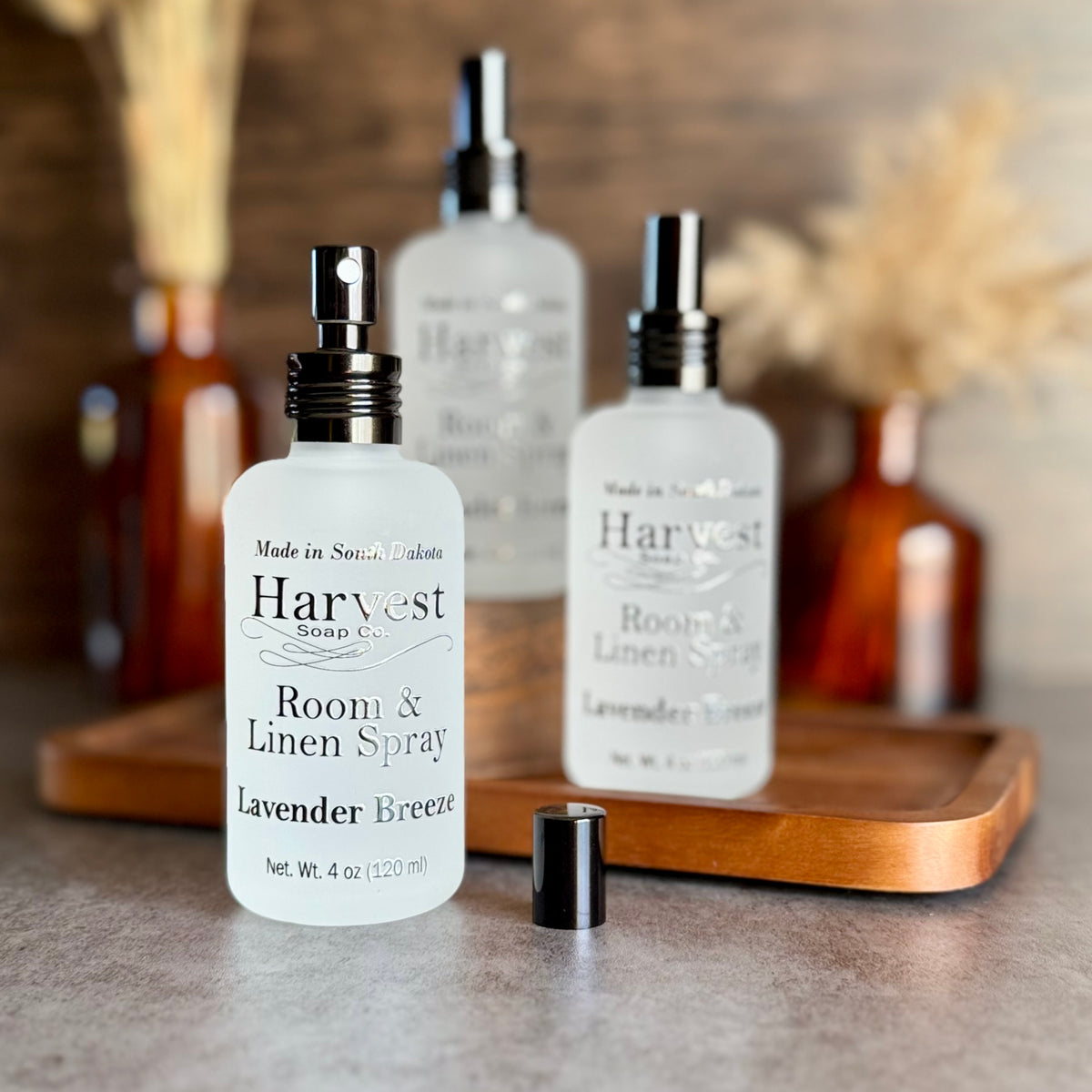 Lavender Breeze room and linen spray by Harvest Soap Company, with a spray bottle and fresh lavender flowers.