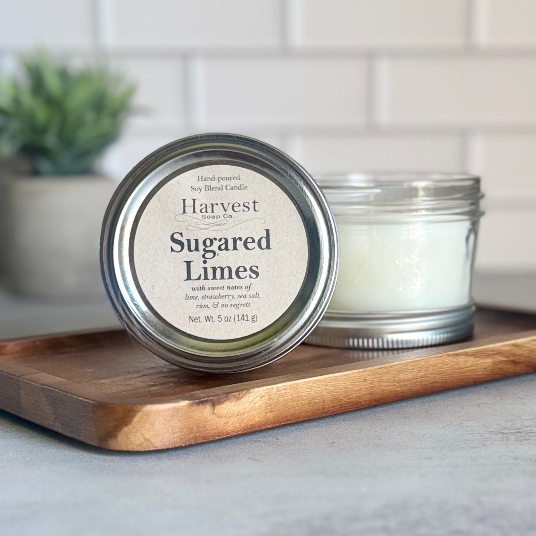 Sugared Limes candle by Harvest Soap Company, showing a white wax candle with a citrus-inspired label and a wooden wick.